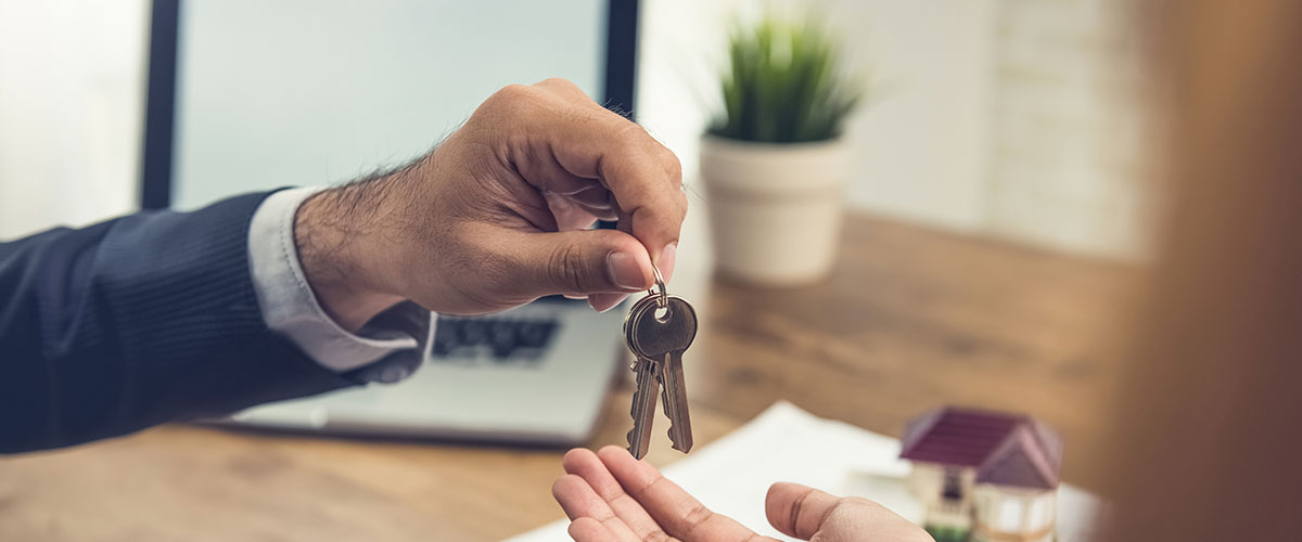 Real estate broker agent giving house keys to client